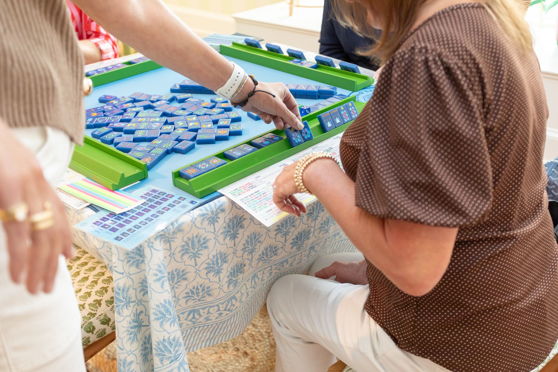 Players arranging mahjong tiles on a patterned table at the Main Line Mahjong studio